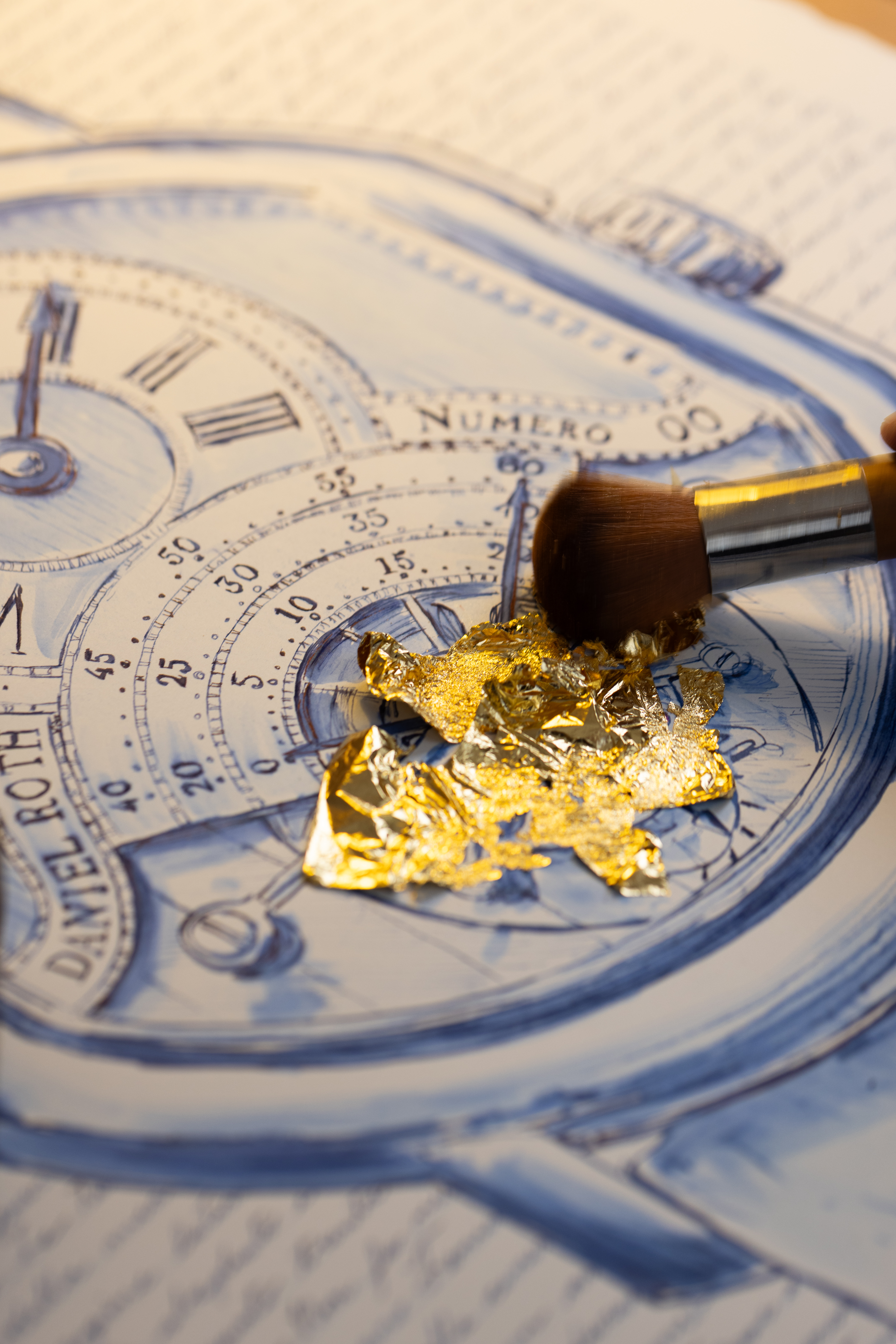 Gold leaf being applied over the blue-ink tourbillon detail.