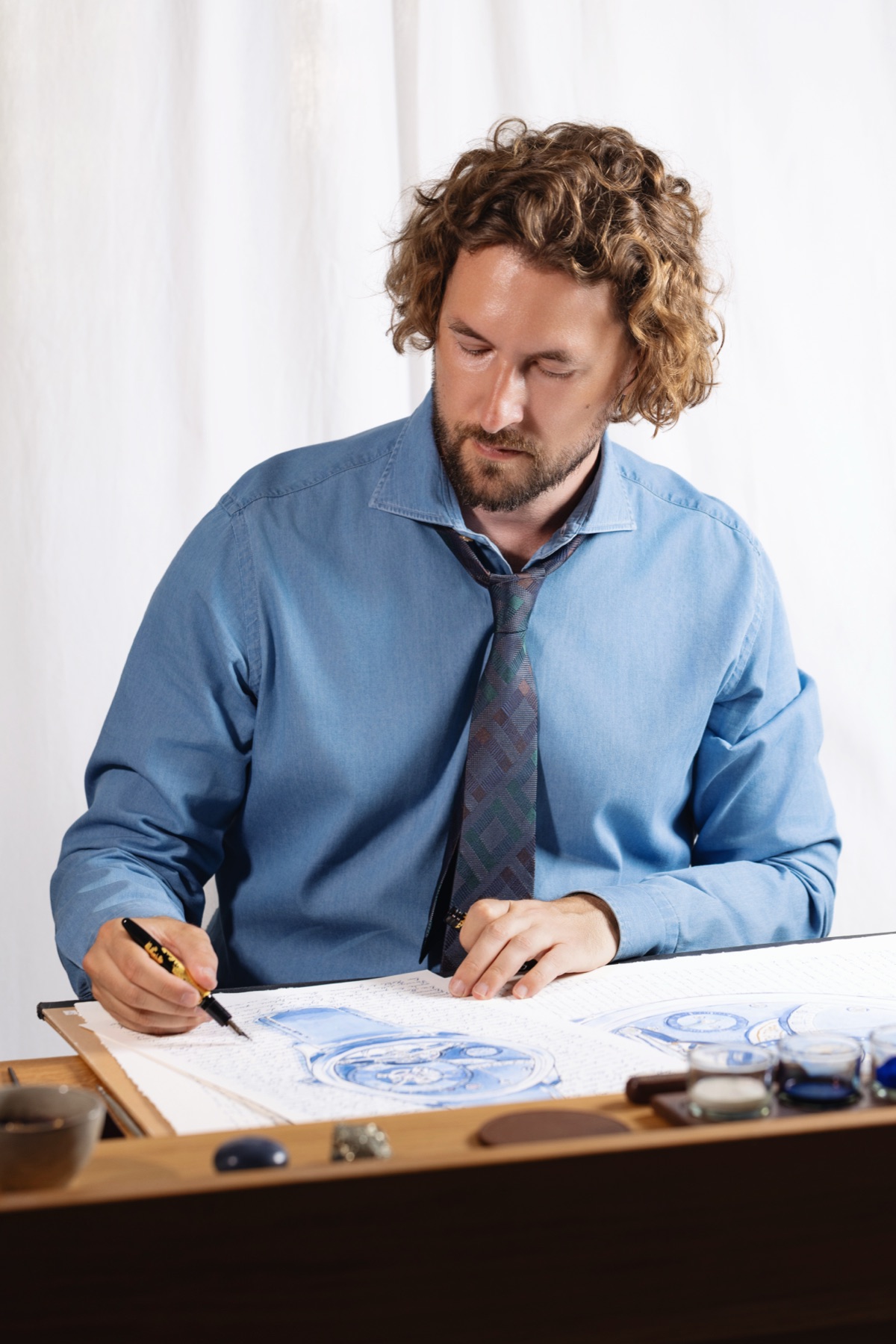 Mauro Carraro working across the blue-ink drawing.