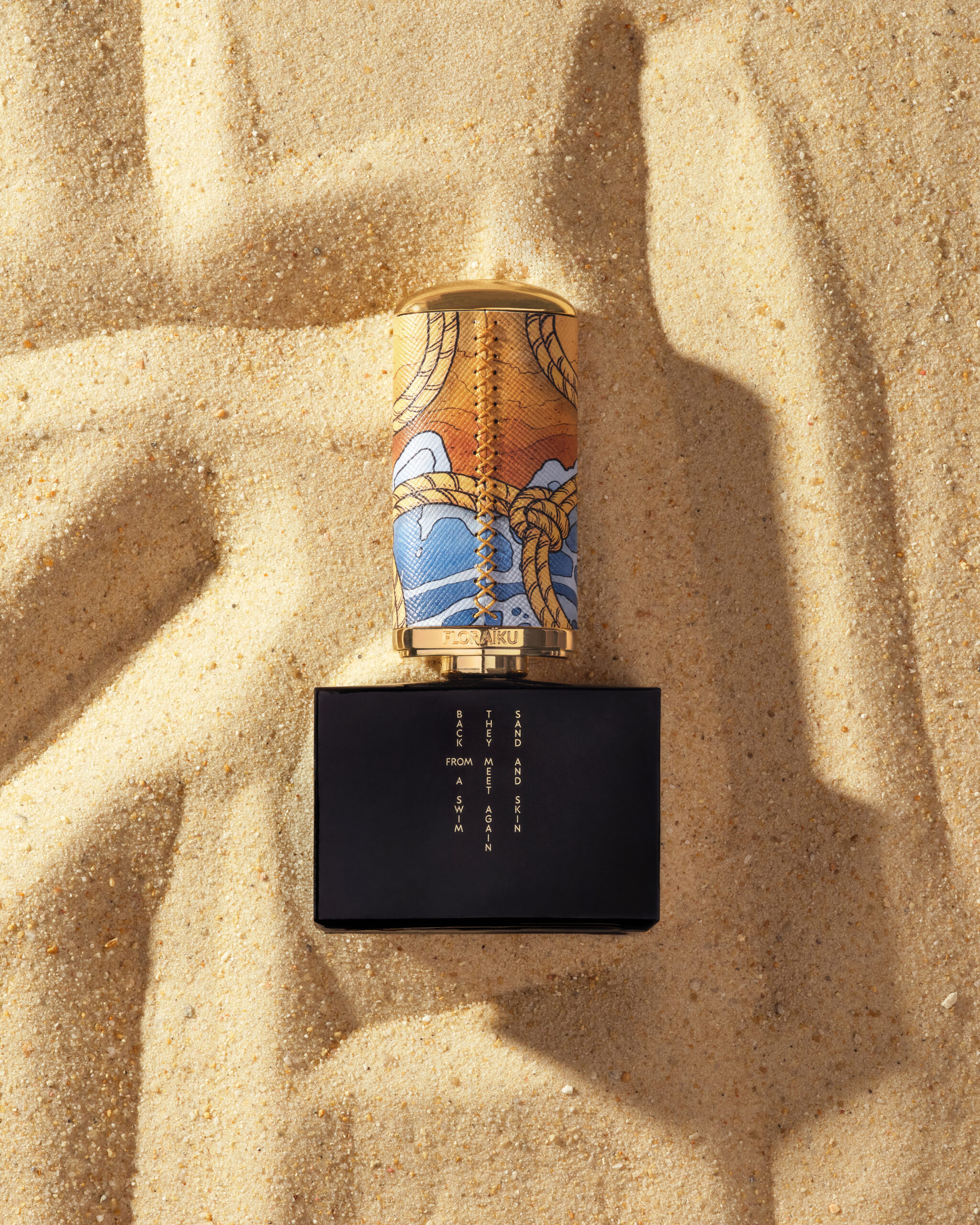 Reverse view of the Floraïku Sand and Skin limited-edition bottle on sand.