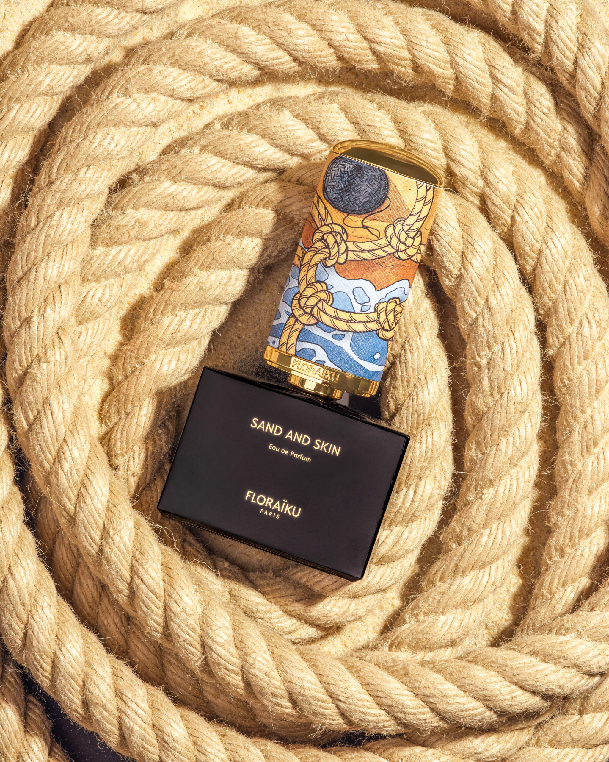 Floraïku Sand and Skin bottle and case with Mauro Carraro's cap illustration, surrounded by rope.