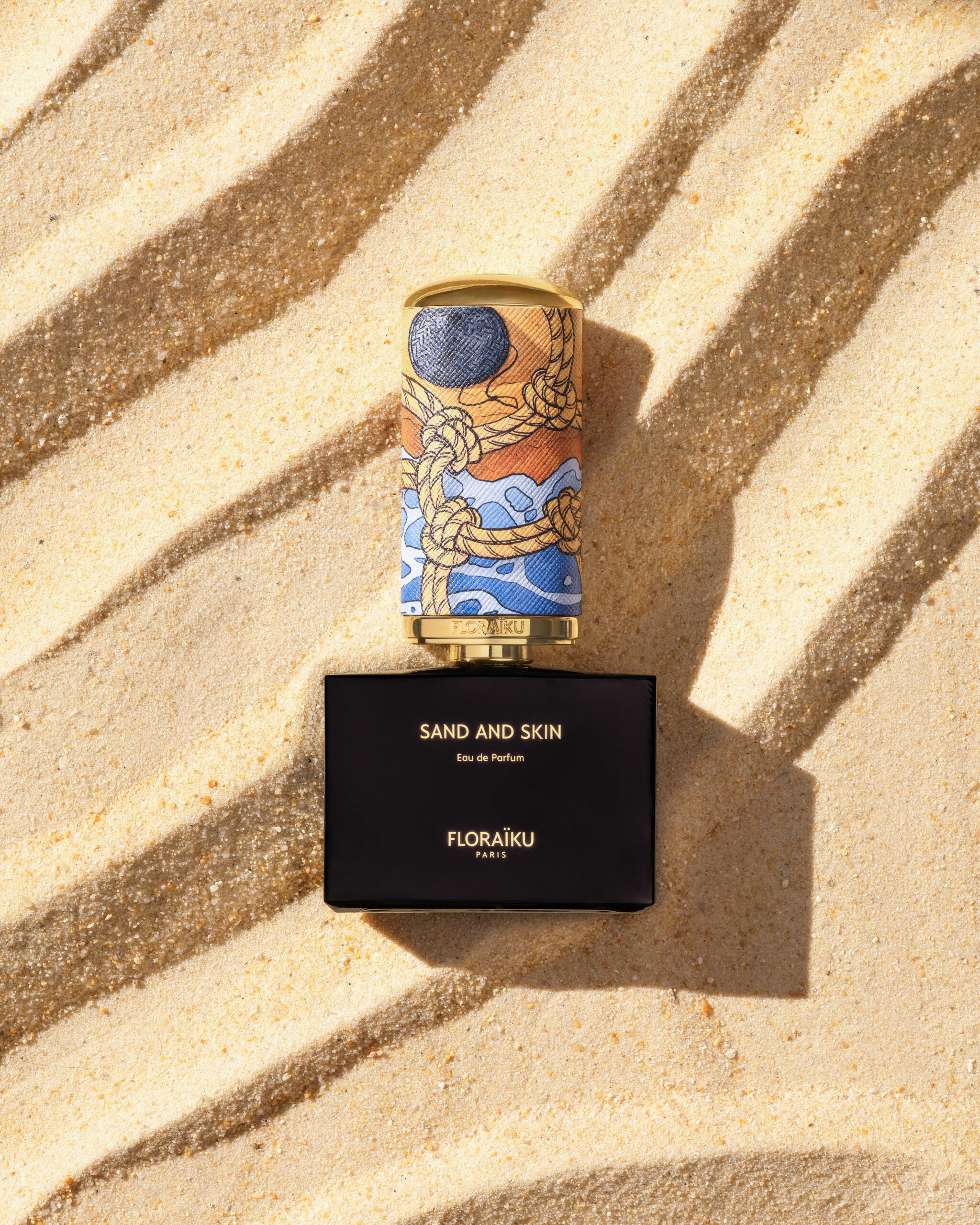 Detail of the Floraïku Sand and Skin limited-edition bottle on sand.