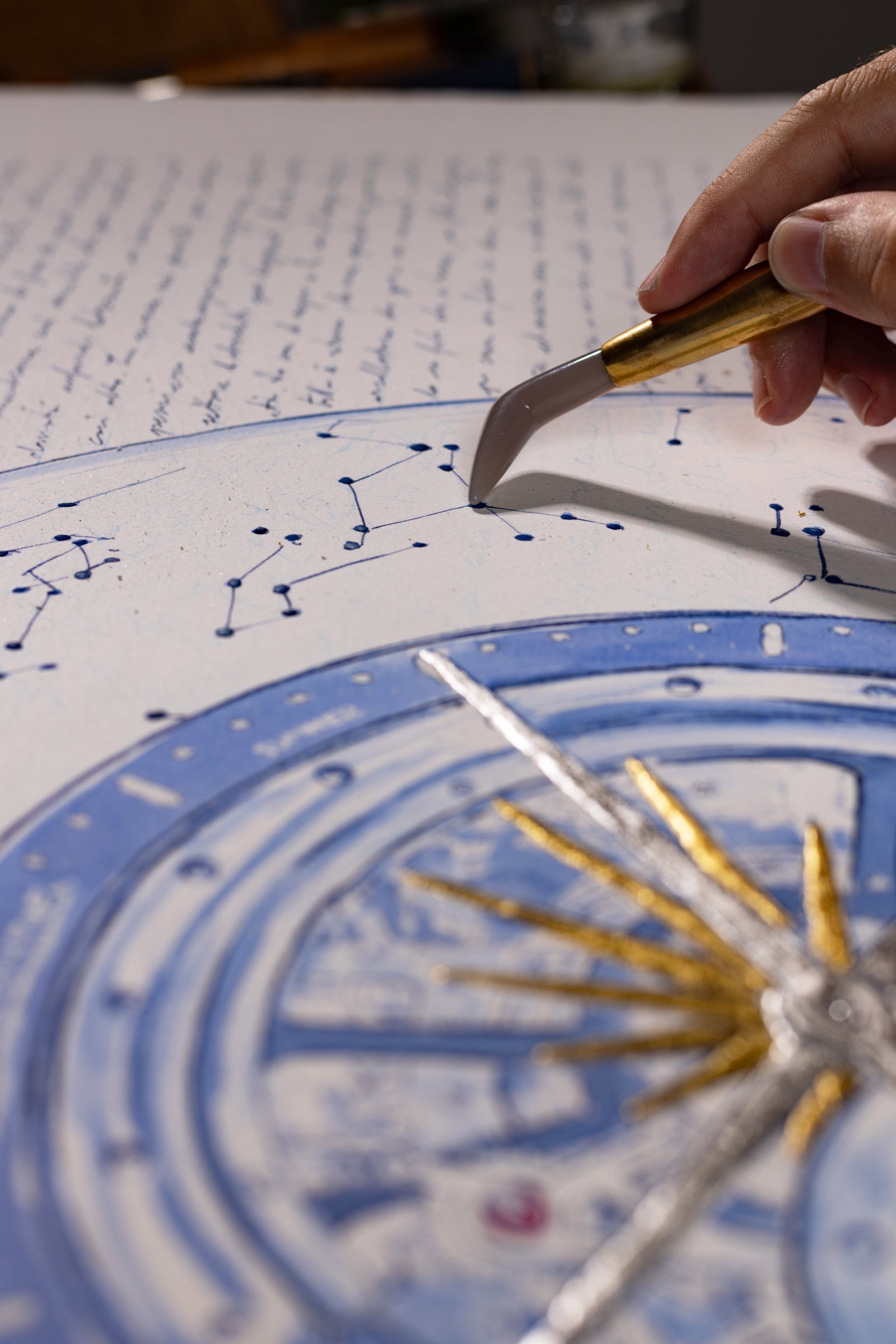 A palette knife touching a raised constellation point on the Atmos drawing.