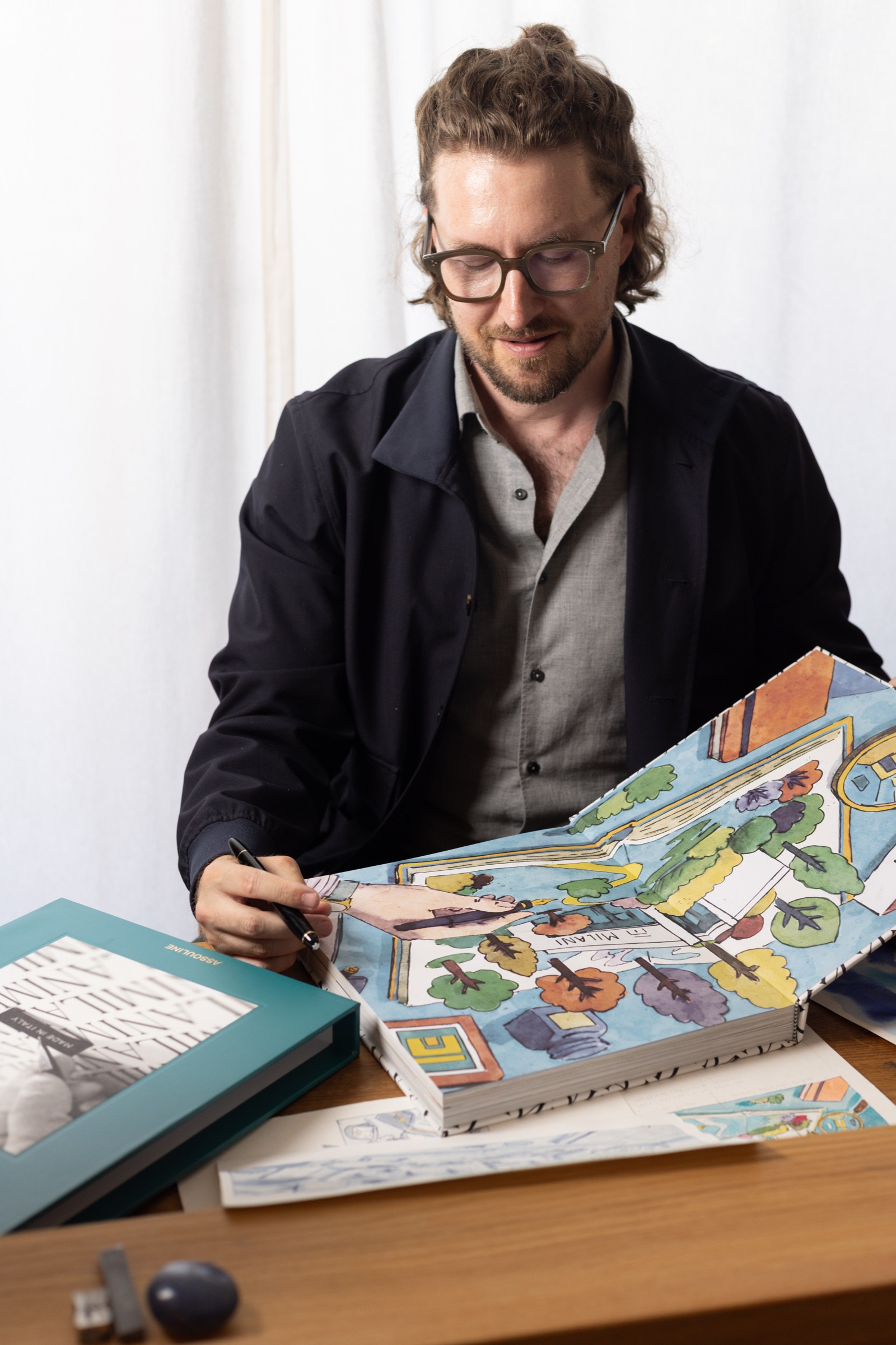 Mauro Carraro opening the Grafiche Milani anniversary book at the studio table. Photograph by Johann Sauty.