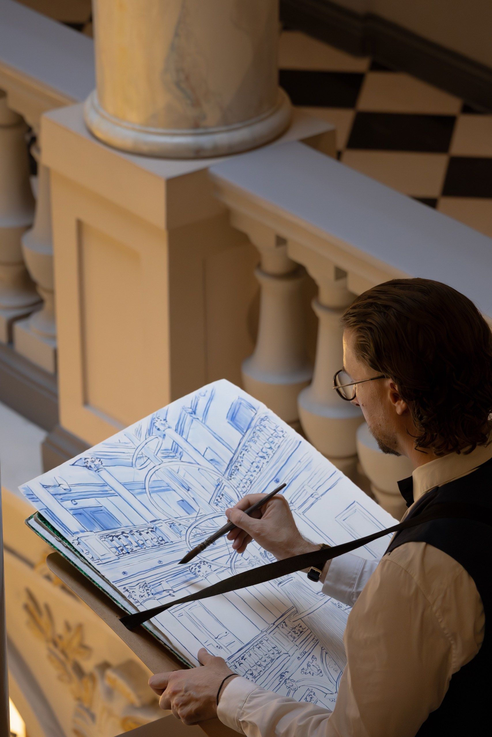 Mauro Carraro working with a brush on the blue-ink chandelier drawing.