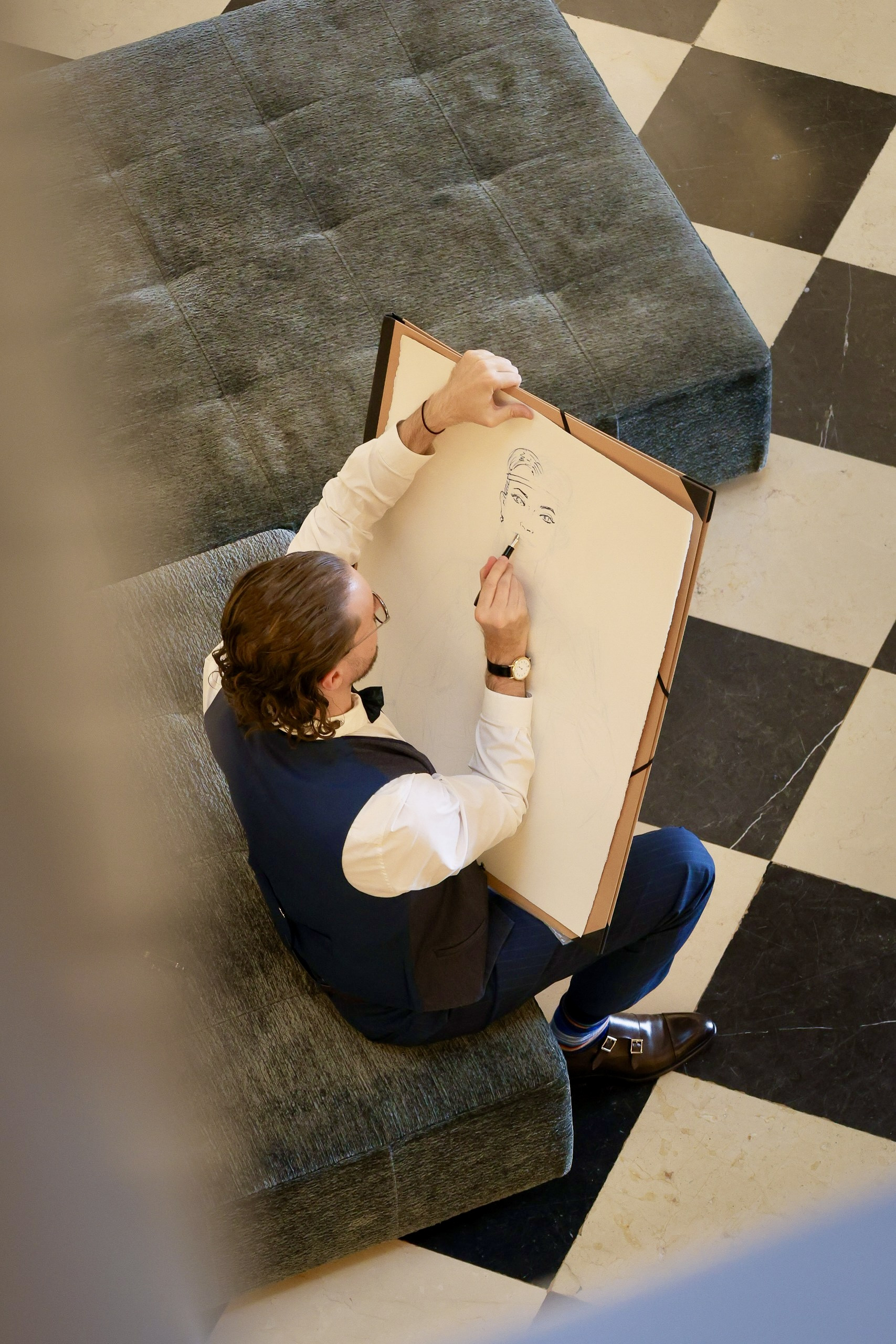 Mauro Carraro seated drawing a portrait at The Ritz-Carlton Geneva.